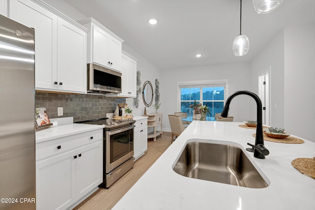 kitchen with a sink, white cabinets, light countertops, appliances with stainless steel finishes, and decorative backsplash