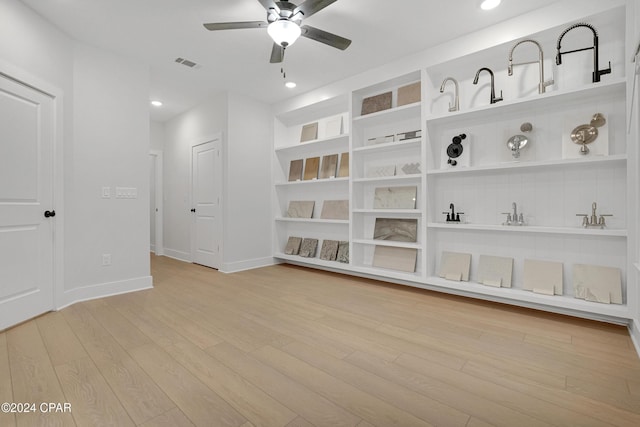 spare room with built in features, visible vents, light wood-style floors, a ceiling fan, and baseboards