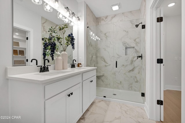 bathroom with double vanity, marble finish floor, a marble finish shower, and a sink