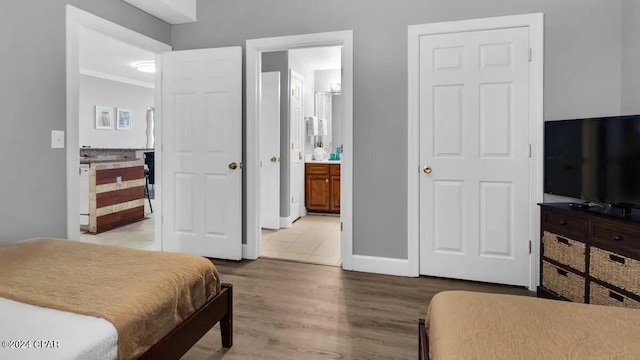 bedroom featuring wood finished floors, ensuite bath, and baseboards