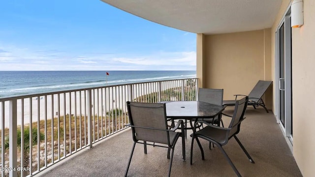 balcony with view of water and beach and outdoor dining area