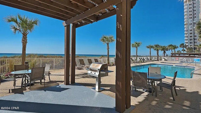 community pool featuring grilling area, a pergola, a patio, and a water view