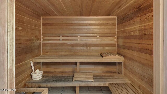 relaxing sauna with tile patterned flooring, wood ceiling, and wood walls