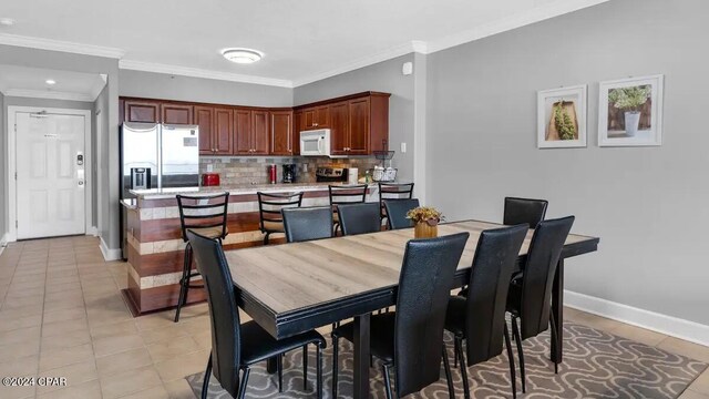 dining area featuring baseboards, ornamental molding, and light tile patterned floors