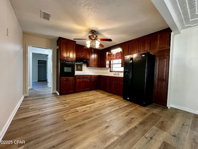 kitchen featuring black appliances, visible vents, under cabinet range hood, ceiling fan, and light wood-style flooring
