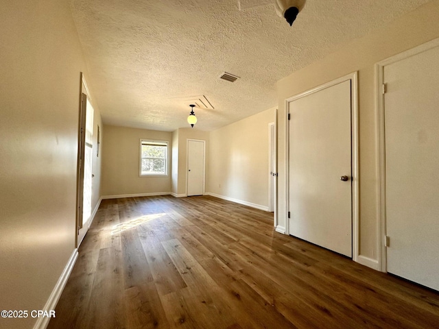 spare room with baseboards, visible vents, a textured ceiling, and wood finished floors