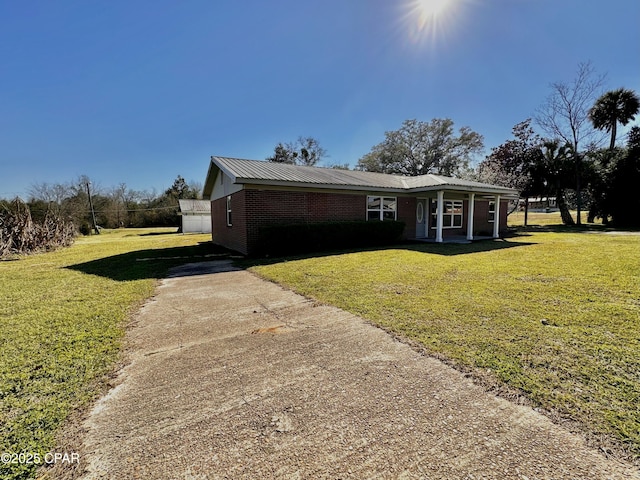 view of front of property with brick siding, metal roof, concrete driveway, and a front yard