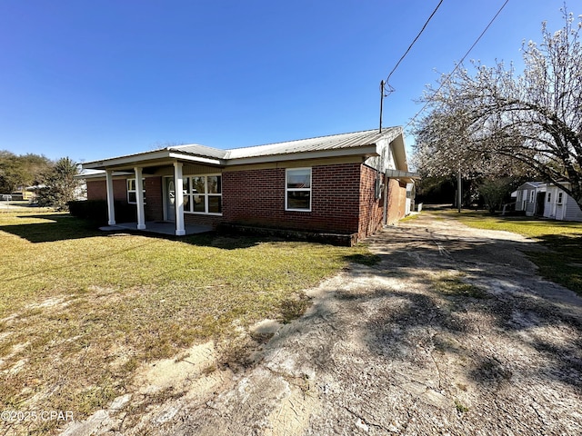 exterior space featuring a yard, brick siding, covered porch, and a storage unit