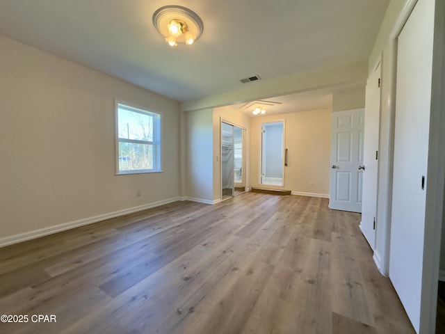 unfurnished bedroom featuring baseboards, a closet, visible vents, and wood finished floors
