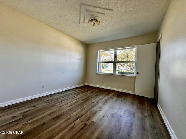 spare room featuring baseboards, dark wood finished floors, and a textured ceiling