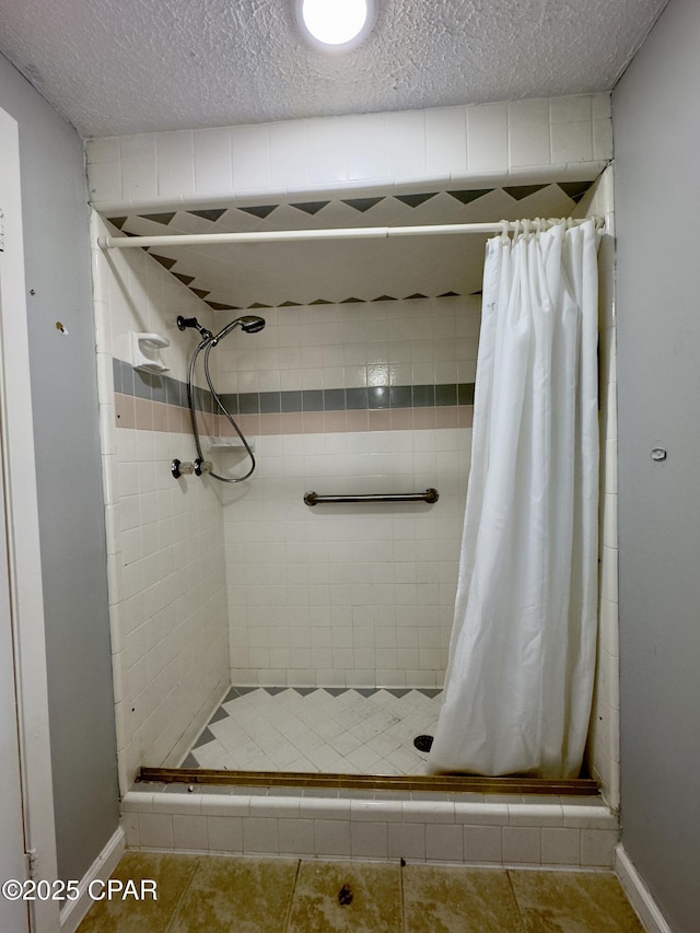 full bath featuring a textured ceiling, baseboards, tile patterned flooring, and a stall shower