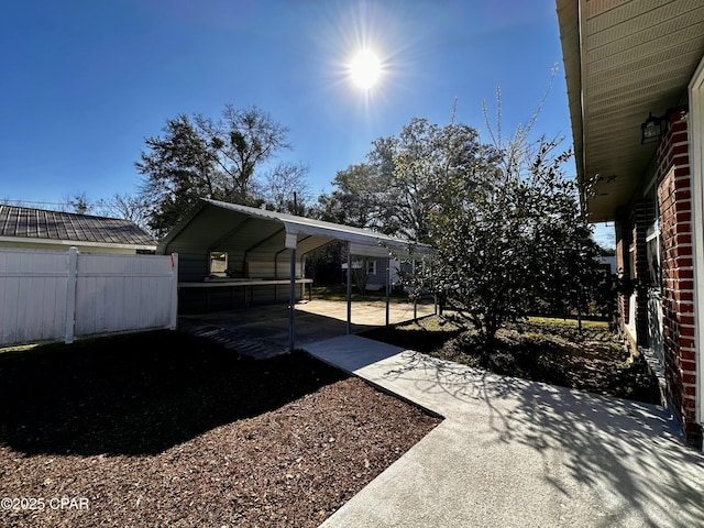 view of yard featuring a detached carport, driveway, and fence