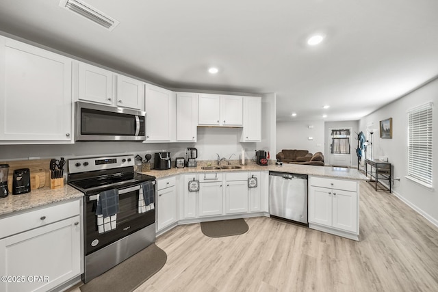 kitchen featuring light wood finished floors, visible vents, stainless steel appliances, white cabinetry, and a sink