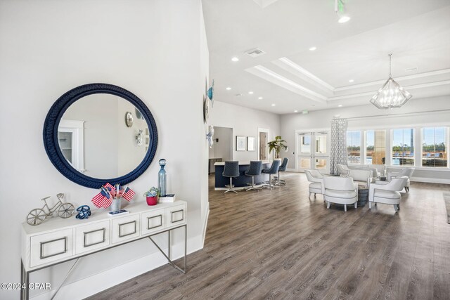 living area with a tray ceiling, a notable chandelier, recessed lighting, visible vents, and wood finished floors