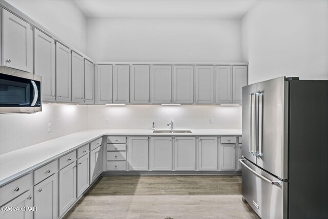 kitchen with light wood-type flooring, appliances with stainless steel finishes, light countertops, and a sink