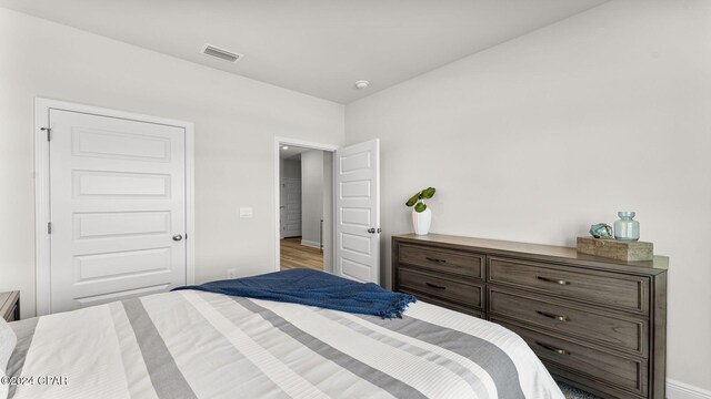 bedroom featuring baseboards, visible vents, and wood finished floors