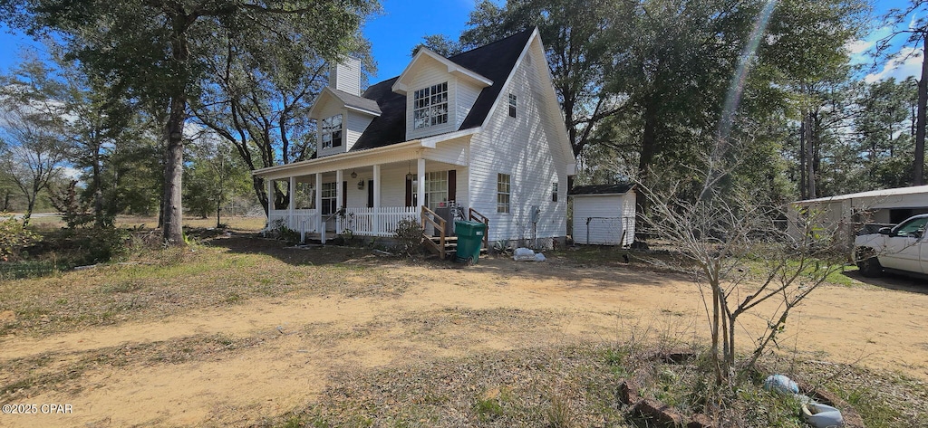 view of front facade featuring covered porch and a chimney