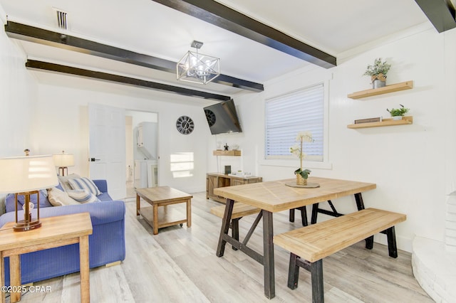 dining area with visible vents, light wood-style flooring, an inviting chandelier, washer and dryer, and beam ceiling