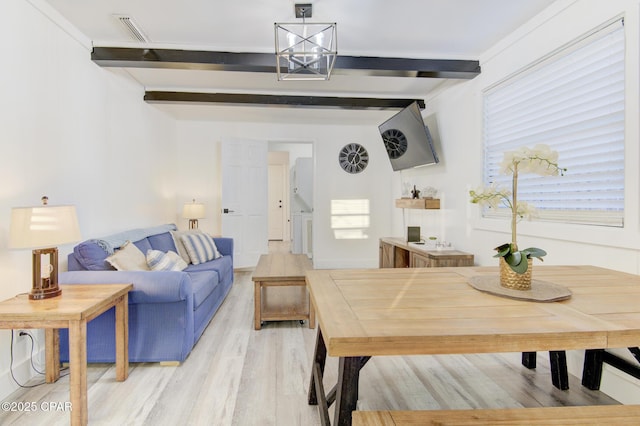 living room with visible vents, light wood finished floors, beam ceiling, and an inviting chandelier