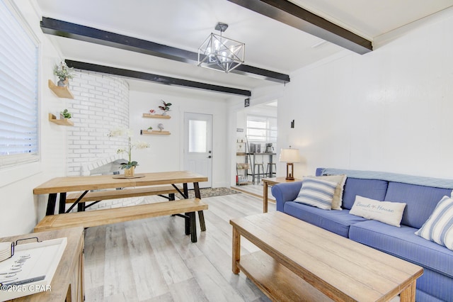 living area featuring light wood-style floors, a chandelier, and beamed ceiling