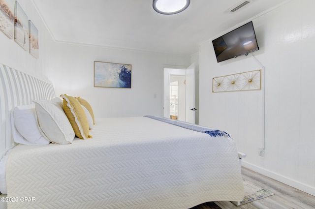 bedroom with visible vents, baseboards, and wood finished floors