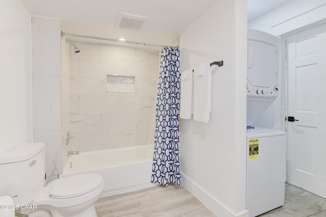 full bathroom with stacked washer and dryer, shower / bath combo, visible vents, toilet, and wood finished floors