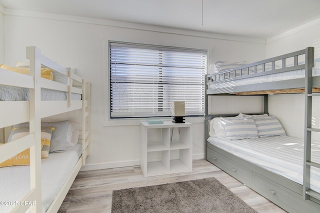 bedroom featuring crown molding, baseboards, and wood finished floors