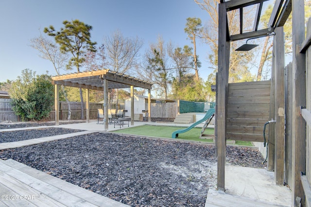 view of yard featuring an outbuilding, a playground, a fenced backyard, a pergola, and a patio area