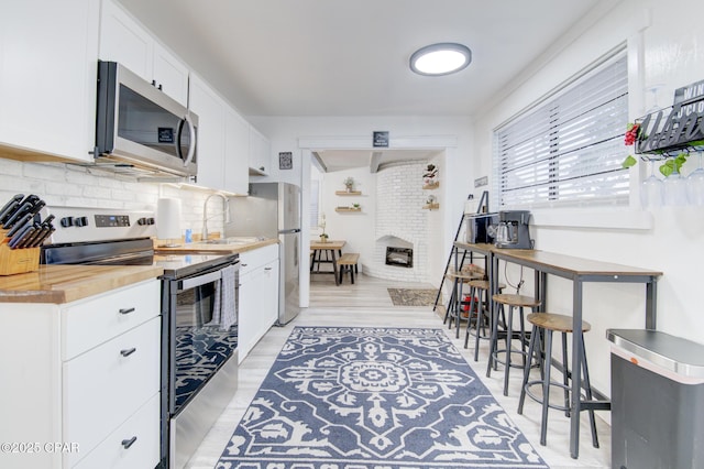 kitchen with a sink, appliances with stainless steel finishes, decorative backsplash, and white cabinets