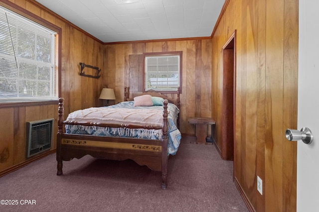 carpeted bedroom featuring heating unit, wood walls, multiple windows, and ornamental molding