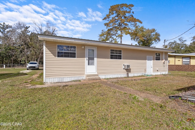 view of front facade with entry steps, a wall unit AC, fence, and a front yard