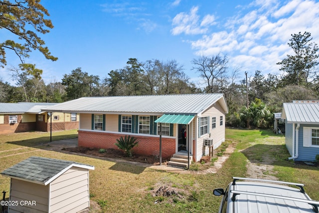 view of front of property with a front yard, brick siding, metal roof, and entry steps