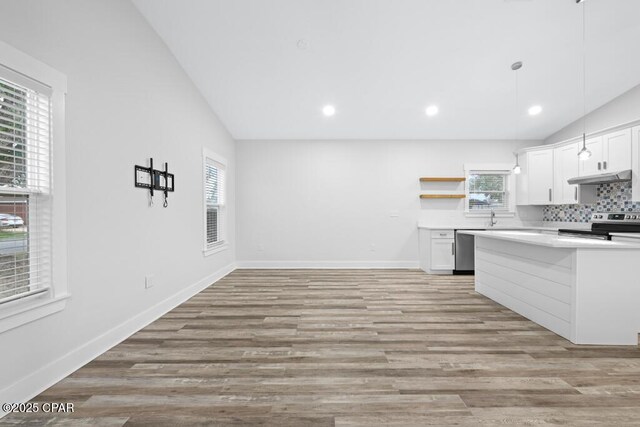 kitchen with stainless steel appliances, light countertops, vaulted ceiling, and under cabinet range hood