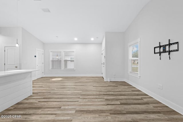 unfurnished living room featuring light wood finished floors, recessed lighting, visible vents, and baseboards
