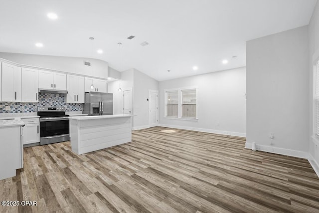 kitchen with lofted ceiling, under cabinet range hood, light countertops, appliances with stainless steel finishes, and a center island
