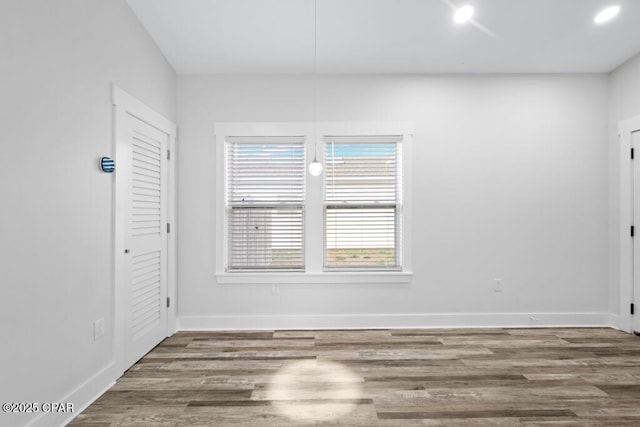 unfurnished room featuring recessed lighting, wood finished floors, and baseboards