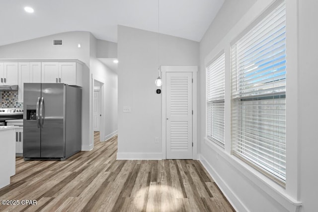 kitchen with lofted ceiling, under cabinet range hood, visible vents, appliances with stainless steel finishes, and light wood-type flooring