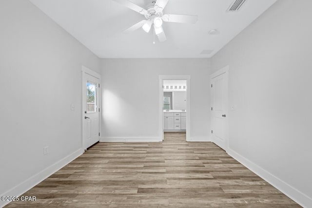 unfurnished room with ceiling fan, light wood finished floors, visible vents, and baseboards