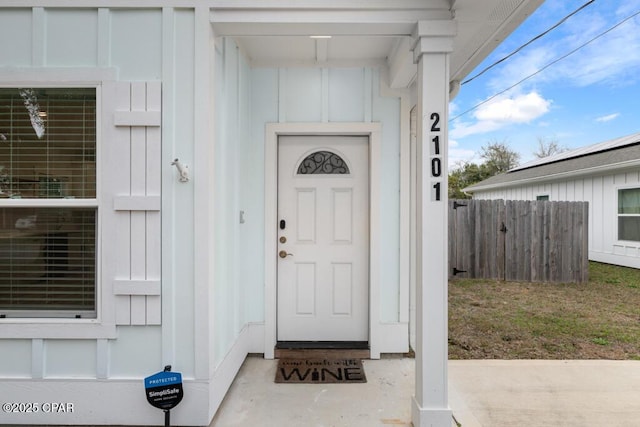 entrance to property with board and batten siding and fence
