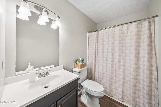 bathroom with a shower with shower curtain, toilet, wood finished floors, a textured ceiling, and vanity