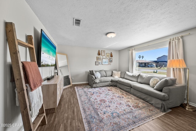 living room with a textured ceiling, dark wood-style flooring, visible vents, and baseboards