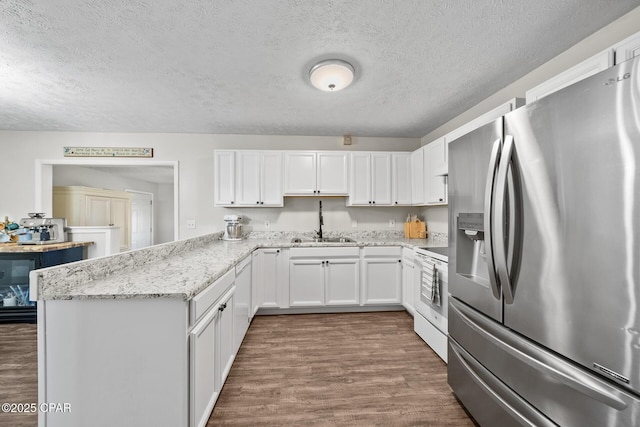 kitchen with a peninsula, dark wood-style flooring, white cabinetry, stainless steel fridge with ice dispenser, and white range with electric cooktop