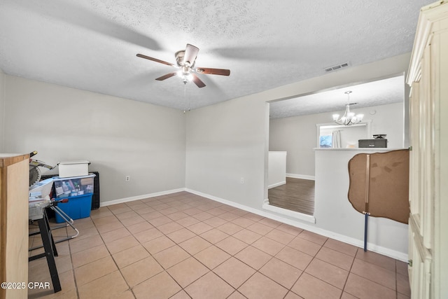 spare room with light tile patterned floors, baseboards, visible vents, a textured ceiling, and ceiling fan with notable chandelier