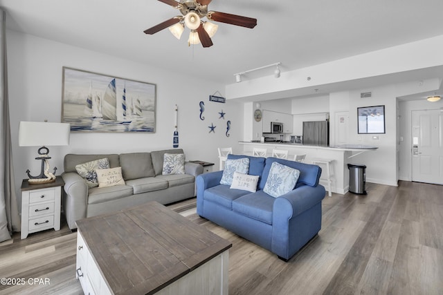 living area with baseboards, visible vents, a ceiling fan, wood finished floors, and track lighting