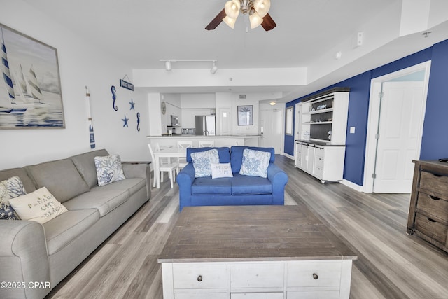 living room with rail lighting, ceiling fan, baseboards, and wood finished floors