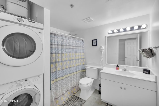 bathroom with curtained shower, toilet, stacked washer and dryer, visible vents, and vanity