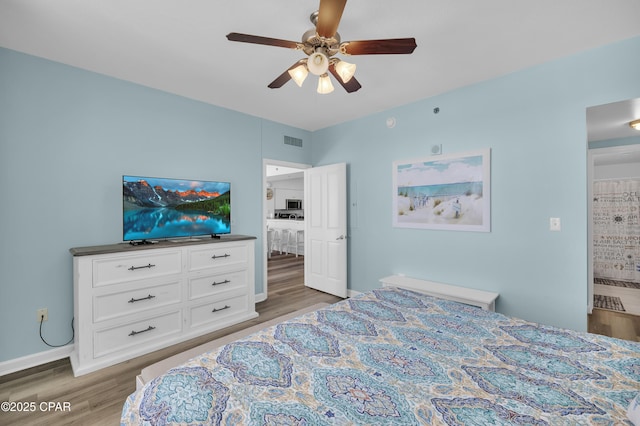 bedroom featuring baseboards, ceiling fan, visible vents, and wood finished floors