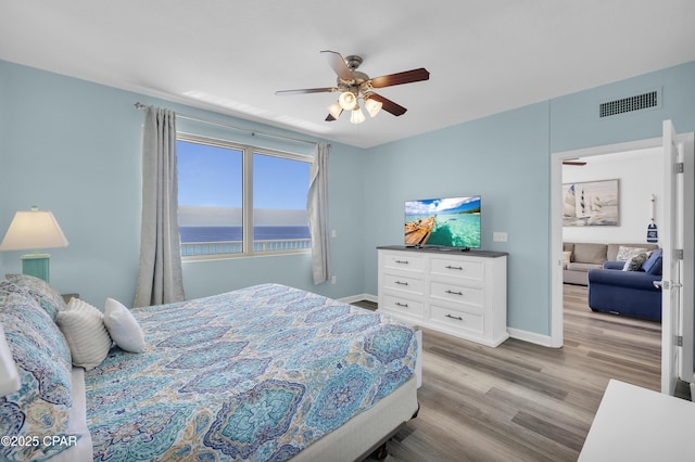 bedroom featuring light wood-style floors, baseboards, visible vents, and ceiling fan