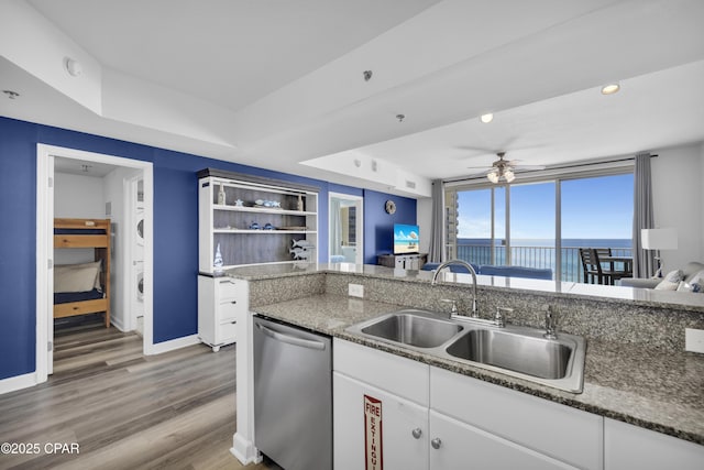 kitchen with dishwasher, open floor plan, light wood-style floors, white cabinetry, and a sink