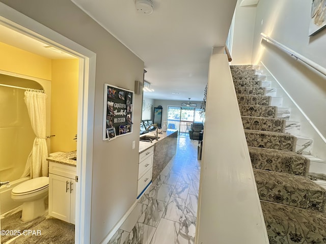 hallway featuring stairway, baseboards, and marble finish floor